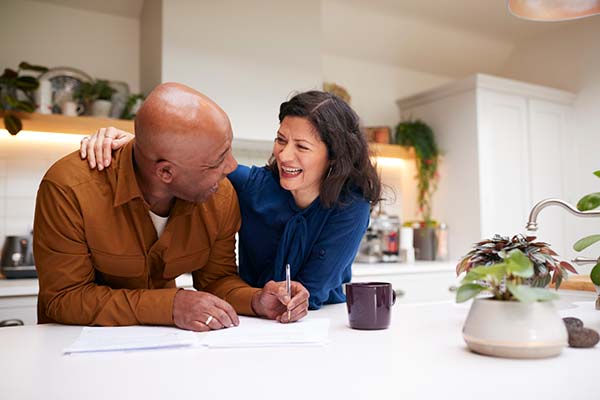 mature couple signing their retirement paperwork in their kitchen